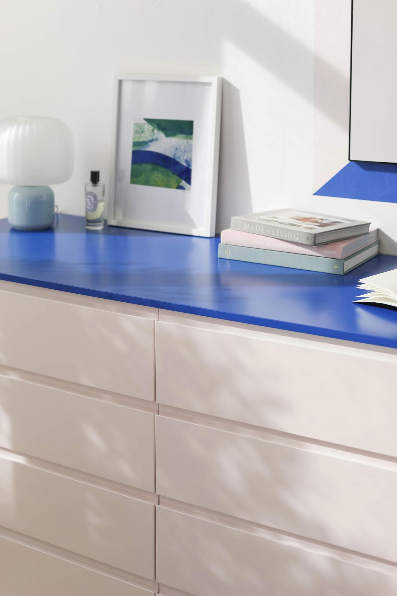 Kommode Beige Rosé und Electric Blau mit Dekoration bestehend aus Büchern, einer Lampe und einem Spiegel.