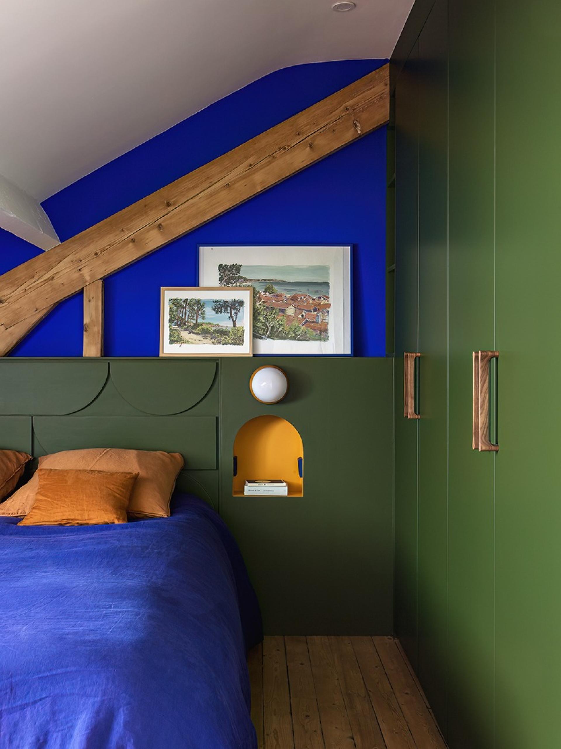 Dachzimmer mit intimer Atmosphäre, blau-gelbe Bettwäsche mit olivfarbenem Kopfteil, mit Nischen